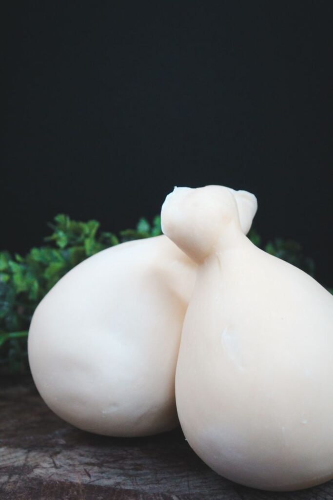 Close-up of fresh provolone cheese elegantly displayed with a dark green backdrop, ideal for culinary themes.
